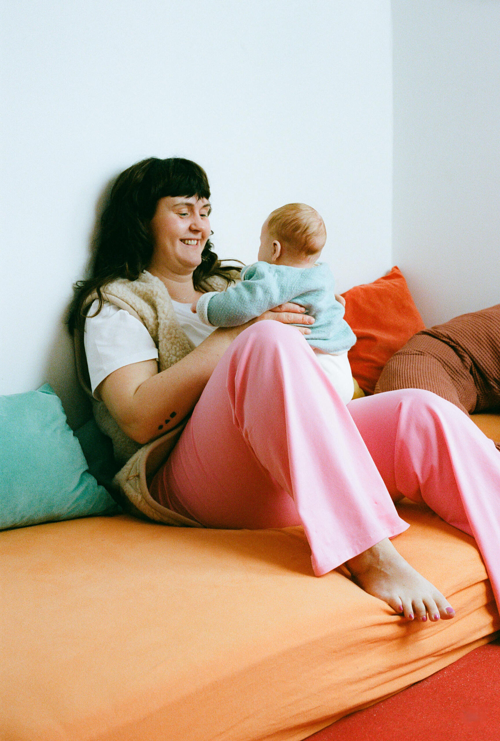 Greta smiles at her baby on her lap Mother and baby sharing a loving gaze while the mother wears MIUMI’s wide-legged maternity pants.