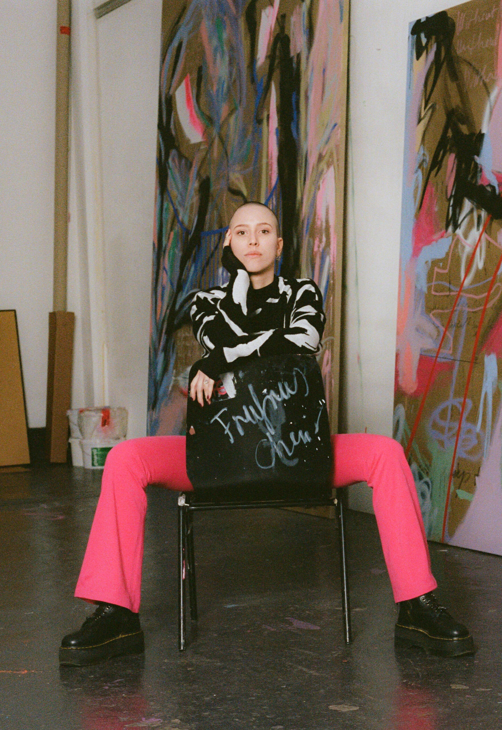 Fruzsina in ihrem Studio Künstlerin sitzt in ihrem Berliner Studio, große abstrakte Gemälde im Hintergrund.