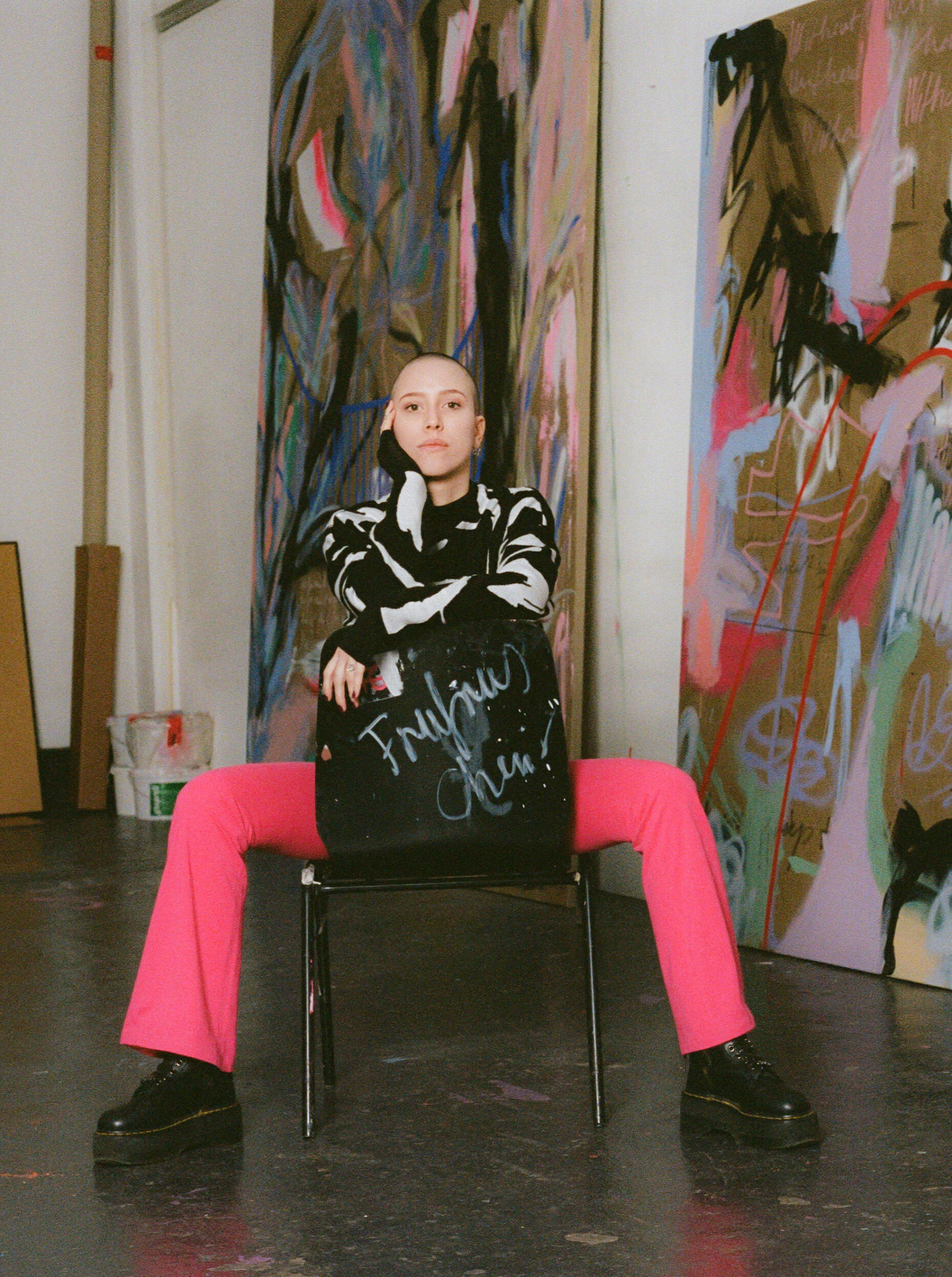 Fruzsina in her studio Artist sitting in her Berlin studio, large abstract paintings displayed in the background.
