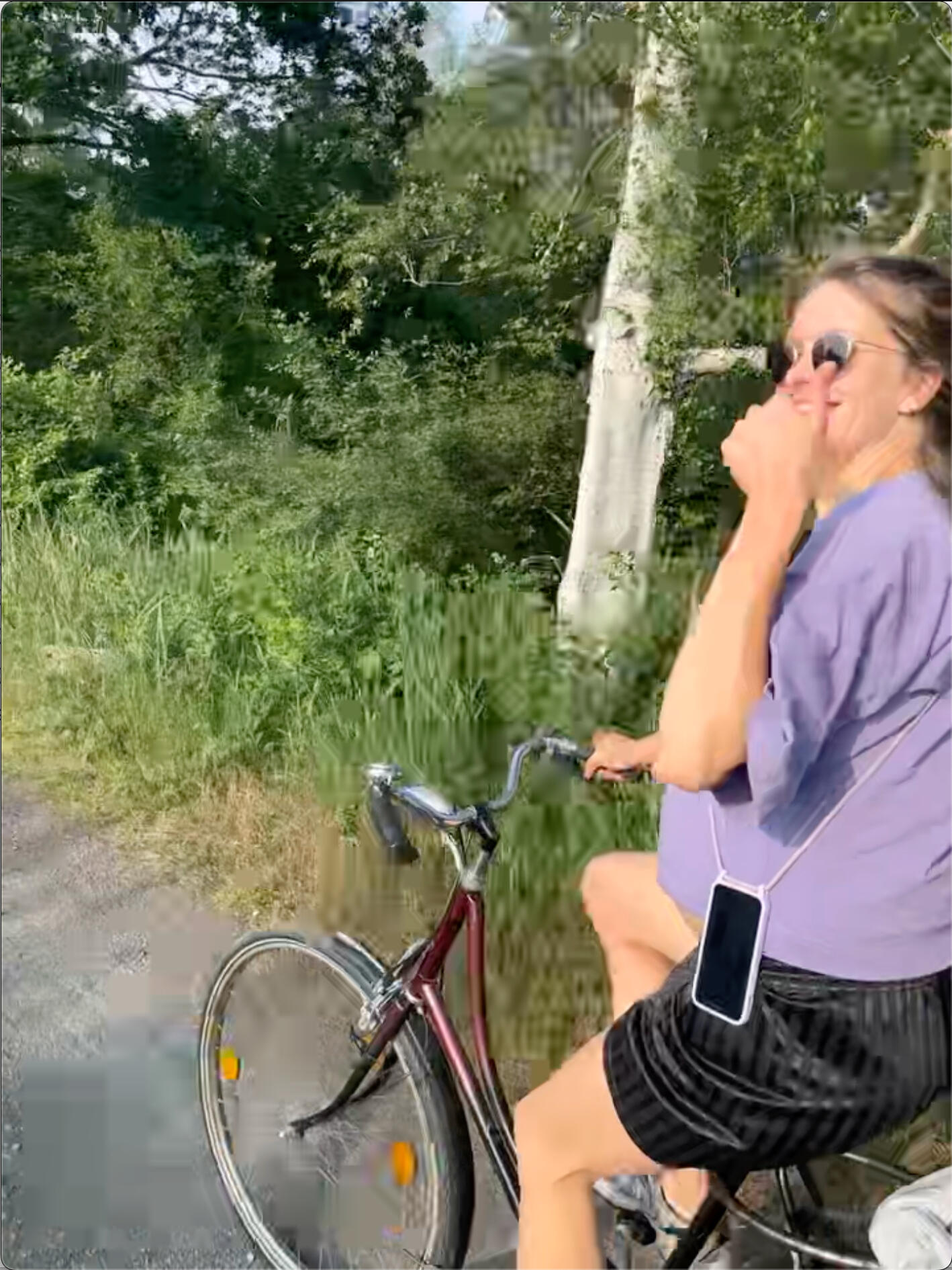 Pregnant Antonia still ridin' that bike Pregnant woman rides a bicycle through green countryside and gives a thumbs up while smiling at the camera.
